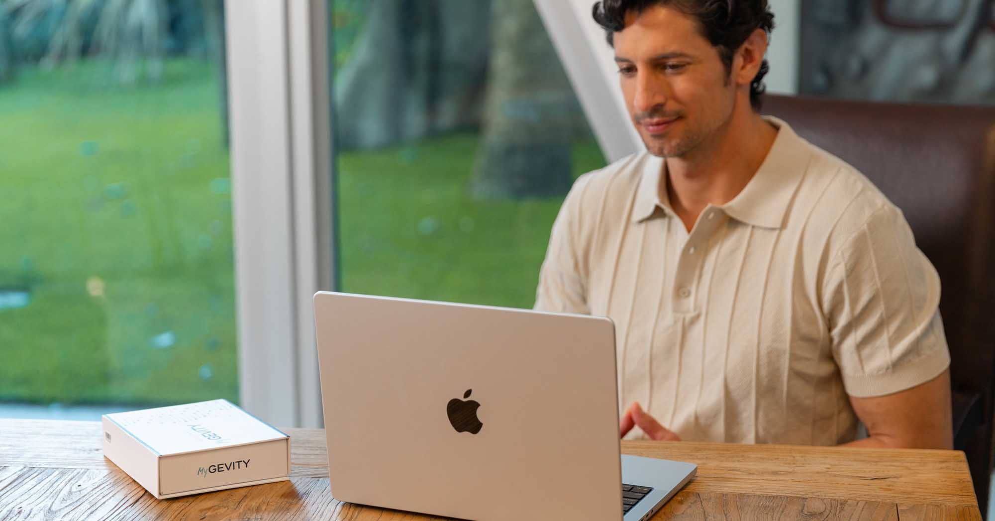 Man reviewing personalized genetic health insights on a laptop next to a MyGevity DNA testing kit