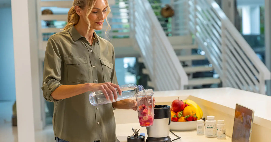 Woman making a healthy fruit smoothie and organizing supplements as part of a wellness routine focused on supporting energy, metabolism, and overall health.