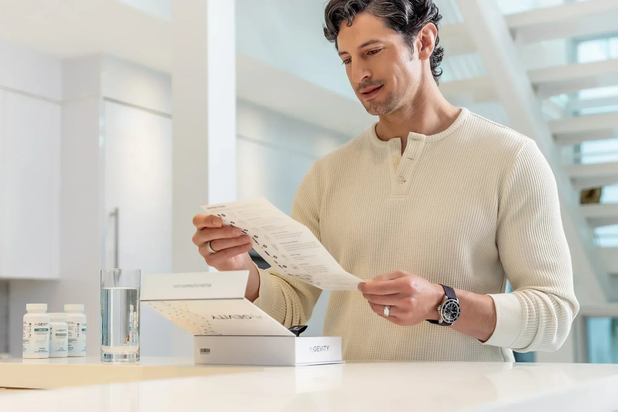 A man reviewing a MyGevity longevity kit and supplement guide in a modern kitchen to support healthy aging and genetic health span.