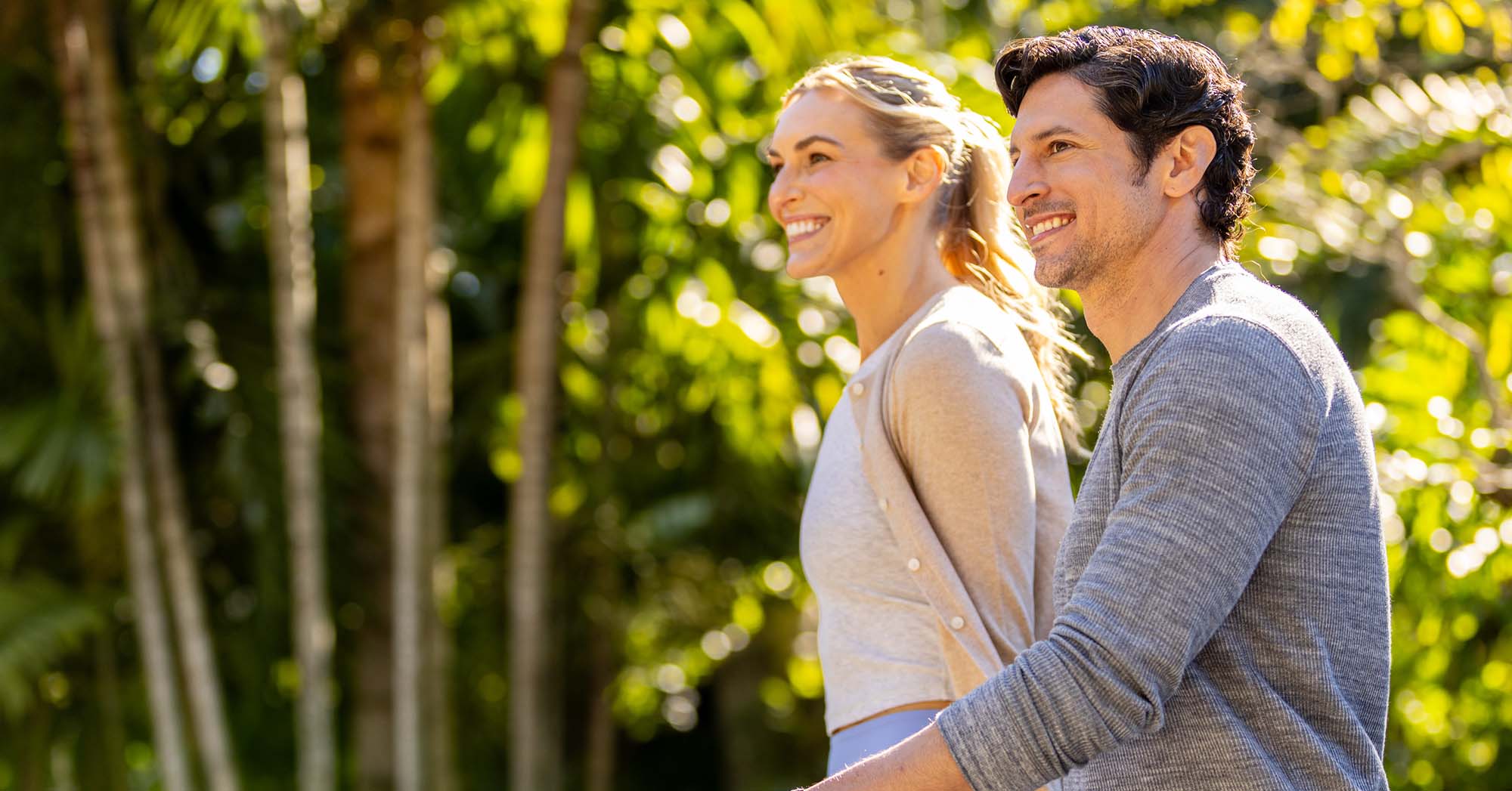 Healthy couple walking outdoors in bright natural sunlight, representing the connection between sunlight exposure, Vitamin D production, genetics, and overall wellness.