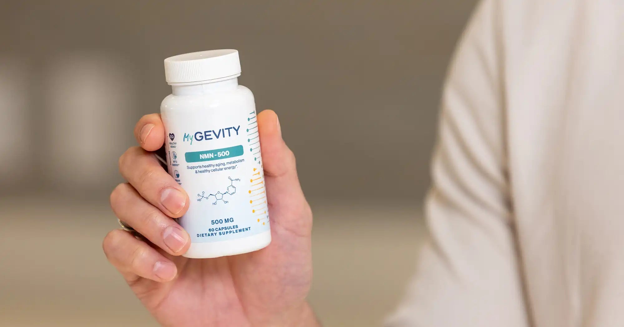 Hand holding a bottle of MyGevity NMN-500 dietary supplement containing 500 mg of NMN