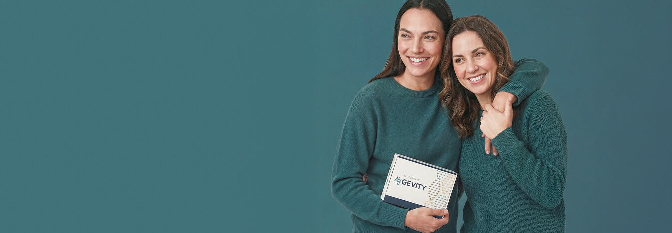 Two women in matching green sweaters holding MyGevity test kit